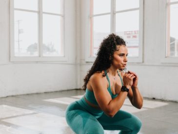 a woman squatting on the floor in a gym