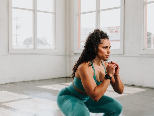 a woman squatting on the floor in a gym