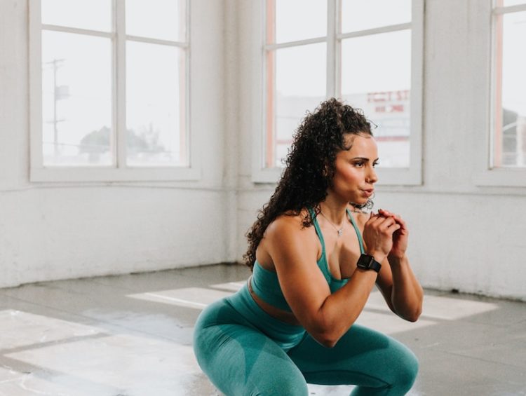 a woman squatting on the floor in a gym